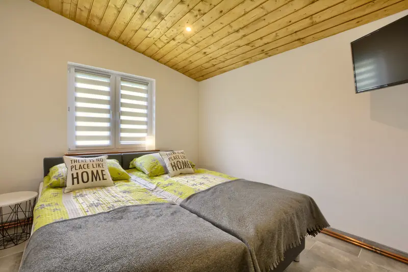 Apartament 4 – sypialnia z podwójnym łóżkiem pod skośnym sufitem z drewnianej boazerii