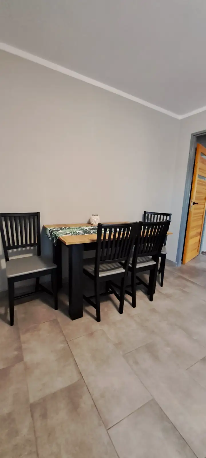 Apartament 5 – jadalnia z drewnianym stołem i czterema krzesłami