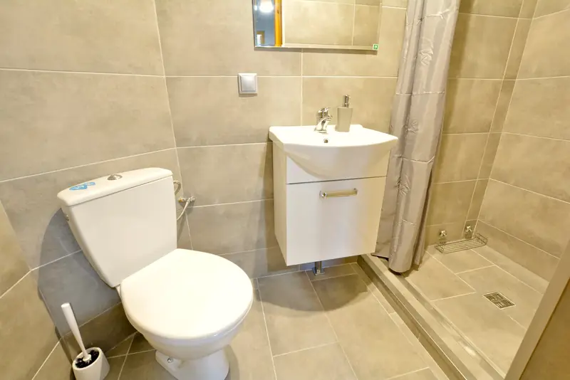 Apartament 1 – łazienka z beżowymi płytkami i prysznicem