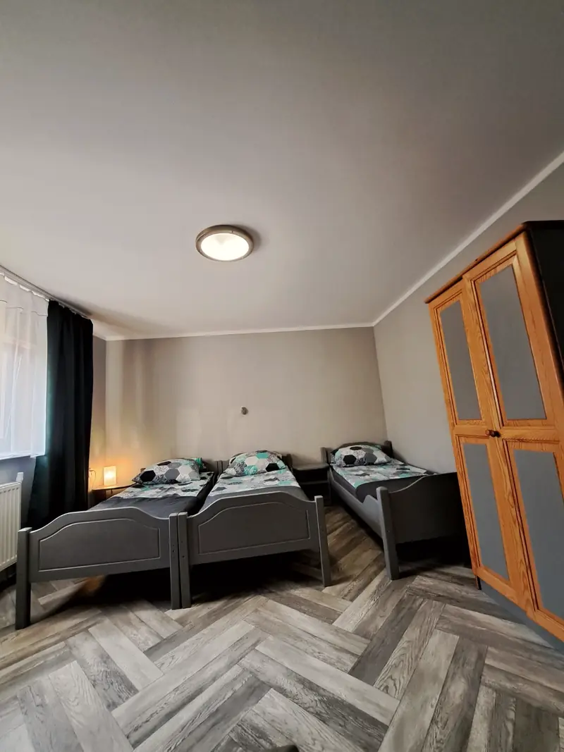 Apartament 5 – sypialnia z trzema łóżkami pojedynczymi i podłogą w jodełkę